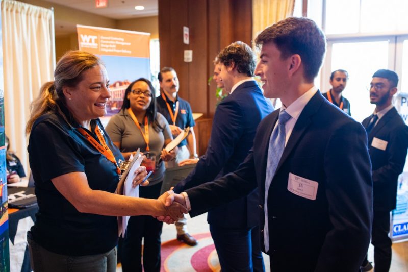 A recruiter shakes hands with a student during a job fair